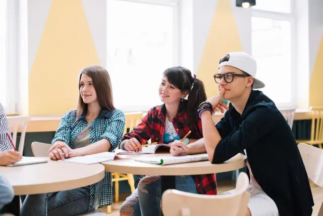 Three students seated at classroom desks