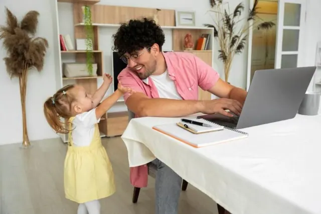 A parent with a child beside a laptop