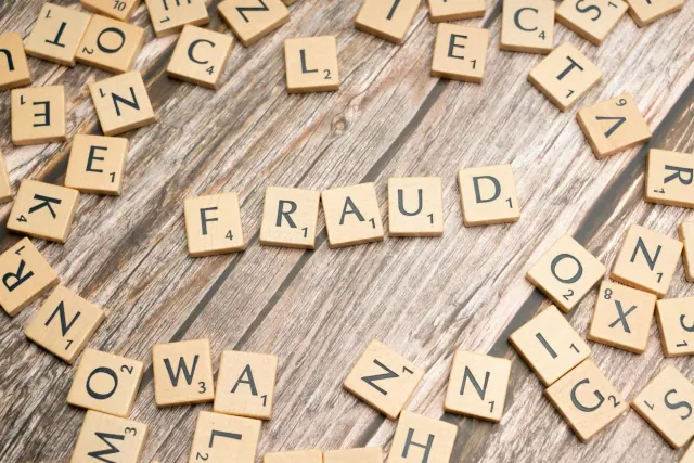 Scrabble blocks spread all over a wooden surface with the main ones spelling Fraid at the center
