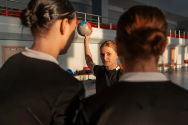Two people in black are pictured approaching a blonde female as they play sports