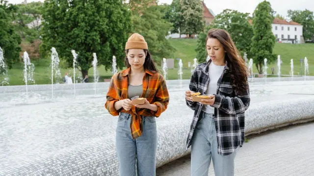 Two people walking beside fountains with food in their hands