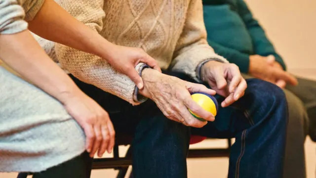 One person supporting another person holding a yellow ball