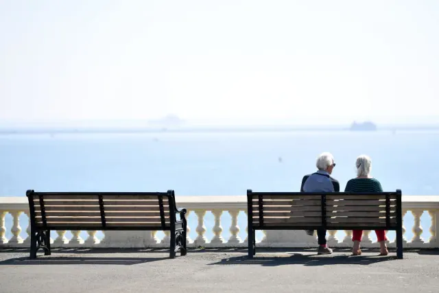 Two people sitting on a bench beside the water