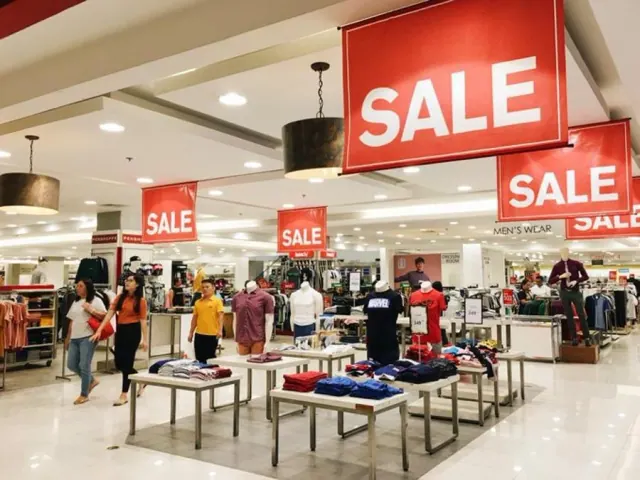 Department store with large signs hanging from the ceiling that read “SALE”