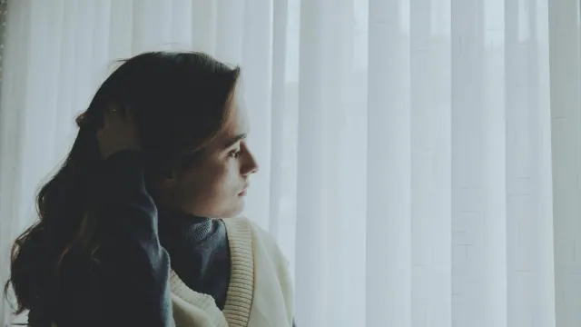 A person looking toward a curtained window