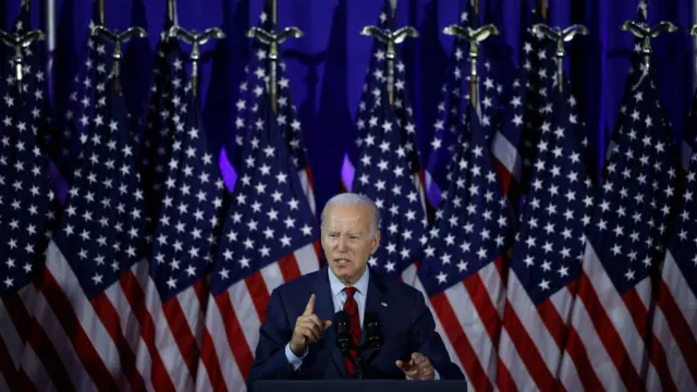 Joe Biden speaking in front of rows of United States flags