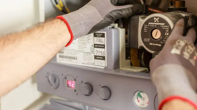 Gloved hands working beside a heating control unit