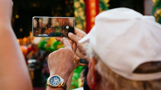 A person in a white cap taking a photograph with a phone