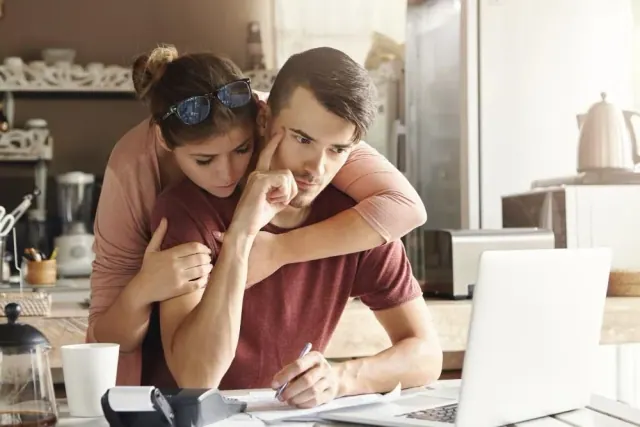 Two people reviewing paperwork beside a laptop