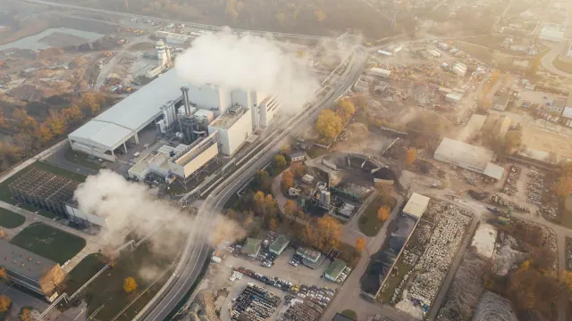 An aerial view of industrial buildings and visible plumes