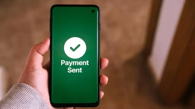 Person holding a phone that reads “Payment Sent”
