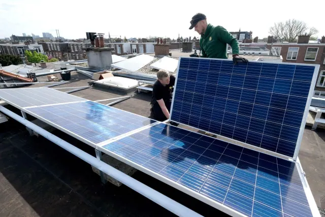 Workers handling solar panels on a roof