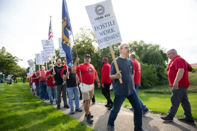 People walking beside a line of UAW signs