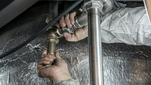 Gloved hands working on pipes in a confined space