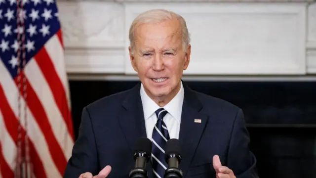 Joe Biden seated in front of a U.S. flag