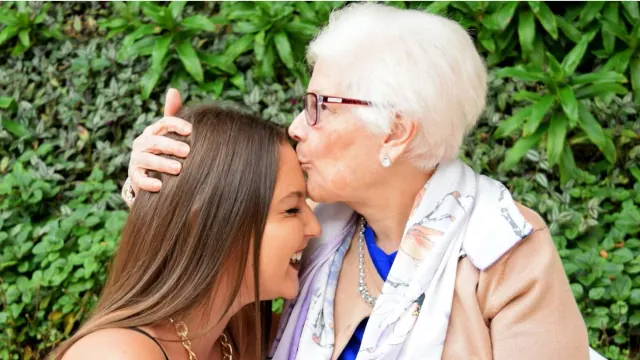 An older woman kissing a younger woman on the head