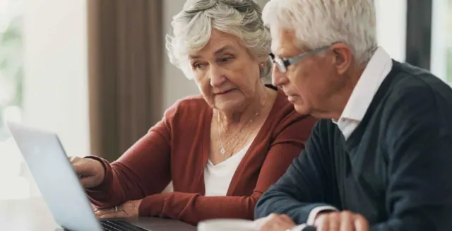 Two older adults looking at a laptop