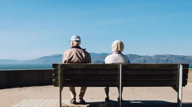 Two people sitting on a bench overlooking water