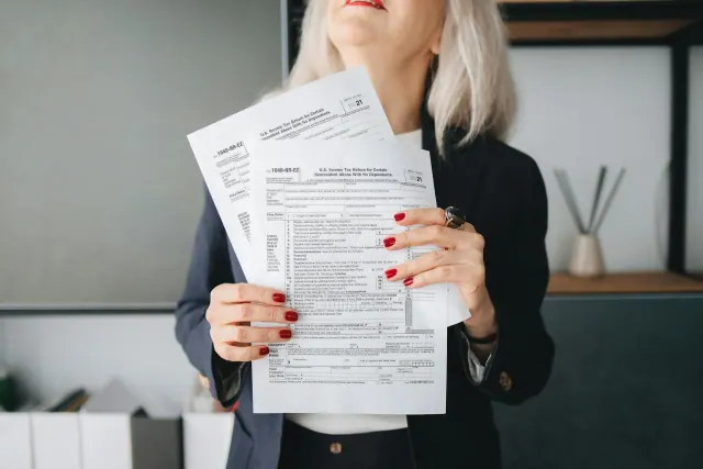 A white haired woman holding several tax documents