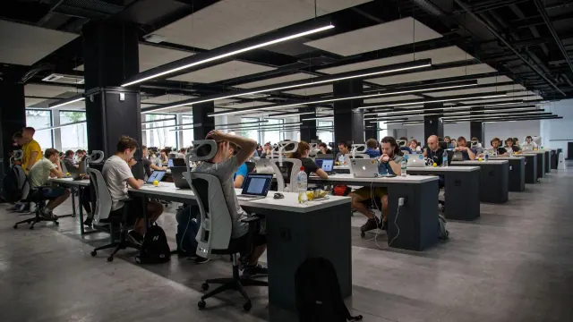 Rows of desks and people working in an open-plan office