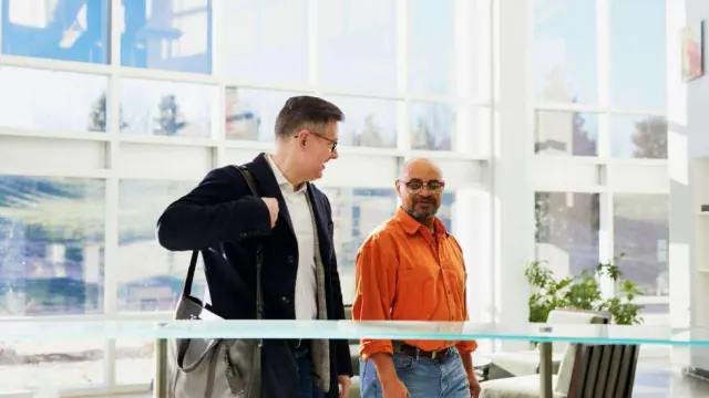 Two people walking through an office corridor