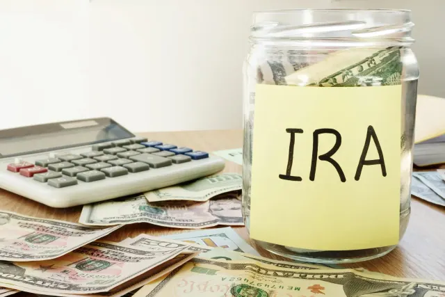 A jar labeled IRA beside currency and a calculator