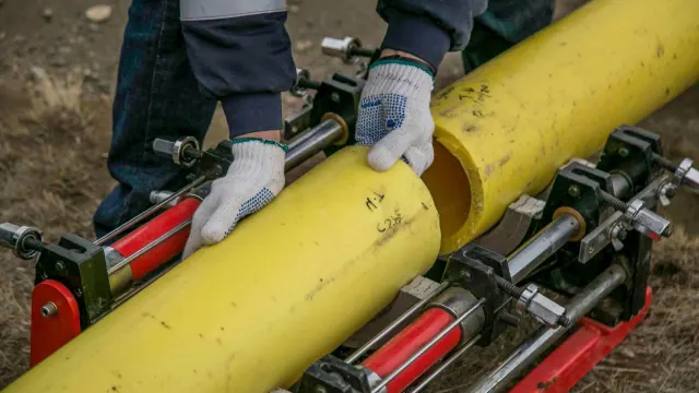Gloved hands working on a large yellow pipe