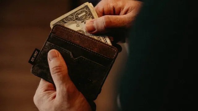 Hands holding a wallet containing cash