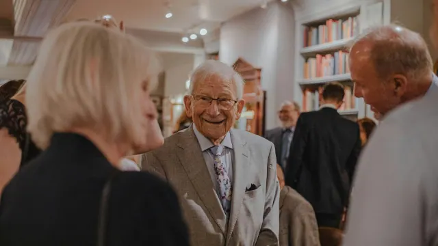 Older people talking around other people in a room.