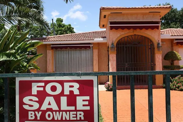 A home with a For Sale by Owner sign on its gate