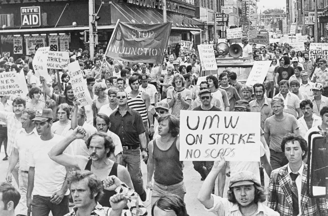A black-and-white photograph of marchers carrying strike signs