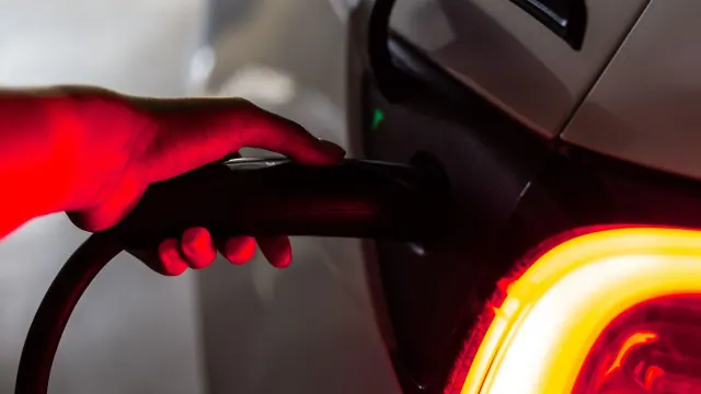 A person holding a connector plugged into a car