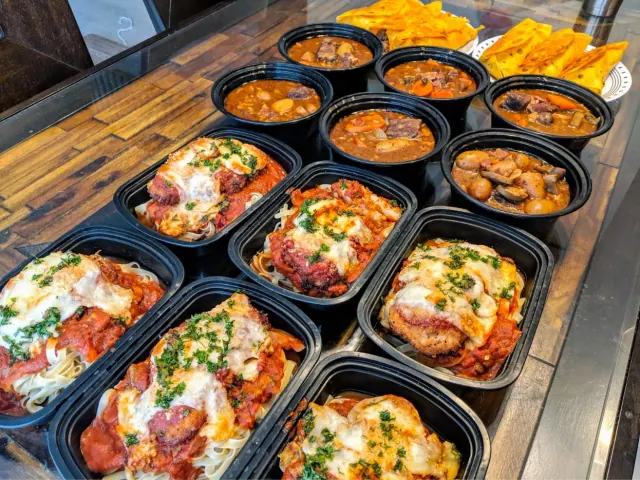 Three lines of pre-plated food lay on a table after an afternoon of meal prep.