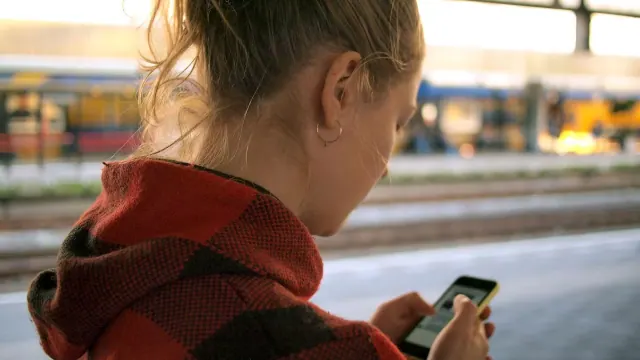 A woman at a train station looking at her phone.