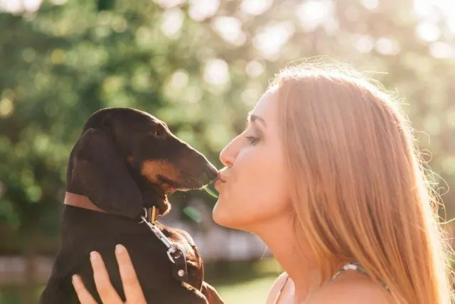 Woman giving her dog a kiss outside in the sun