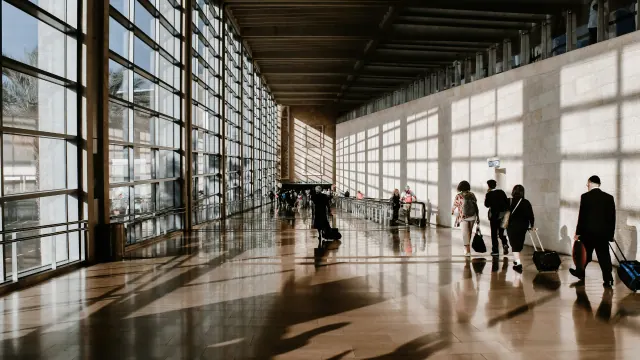 Travelers walking through a sunlit airport terminal