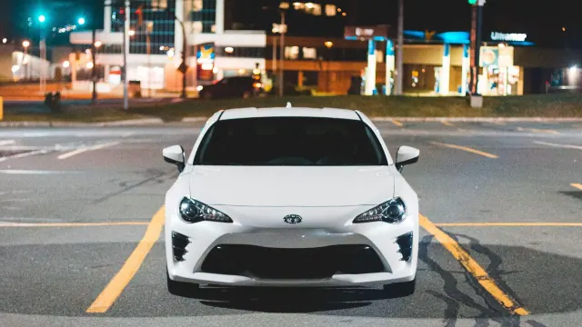 A white car parked near a gas station at night
