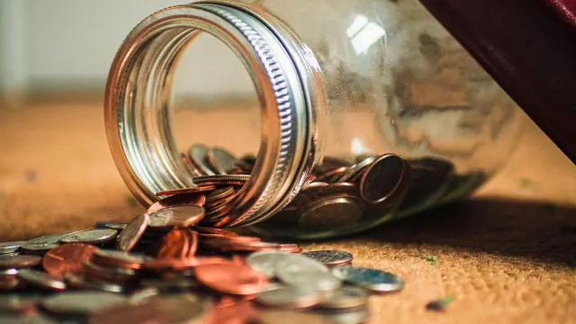 Coins spilling from a glass jar
