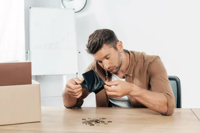 A man examining a wallet with coins on the table