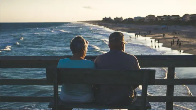 Two people seated on a bench overlooking the sea