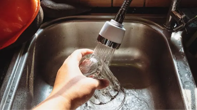 Water running into a glass at a kitchen sink