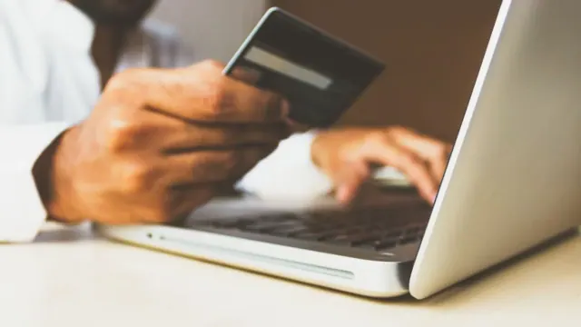 A person using a bank card beside a laptop