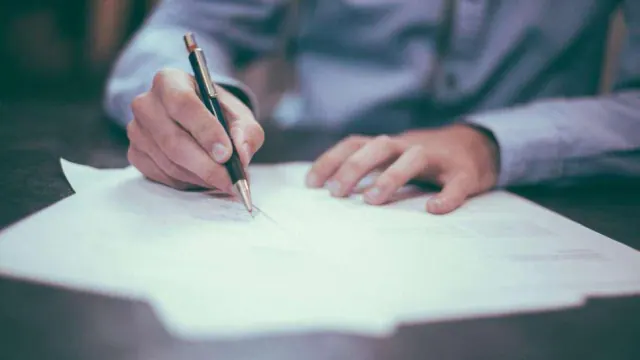 A person writing on papers at a table