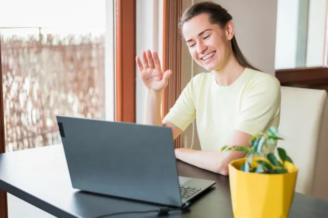 A woman is pictured waving to her camera as she takes a video call