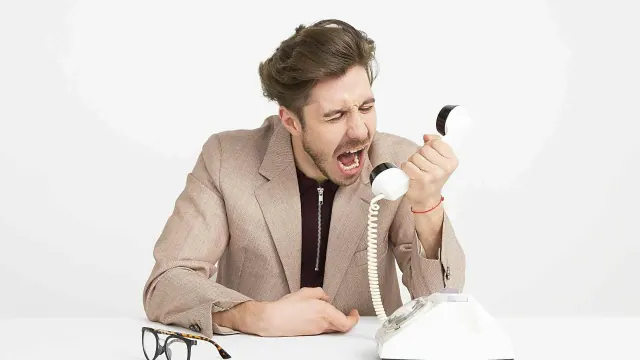 A man holding a telephone handset with his mouth open
