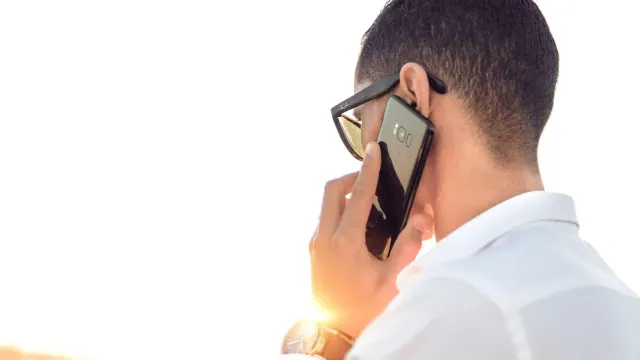 A man with his back to the camera on a phone call. He is holding the phone to his ear.