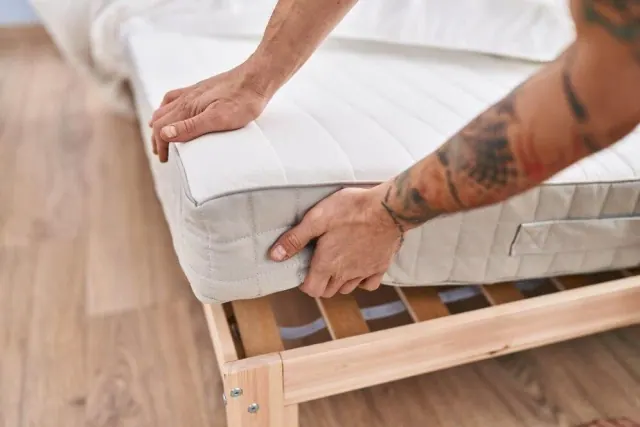 Man picking up the side of a mattress