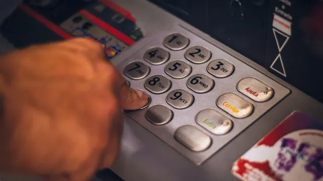 A hand using an ATM keypad