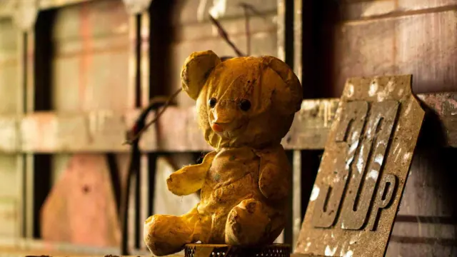 A teddy bear on a wooden bench