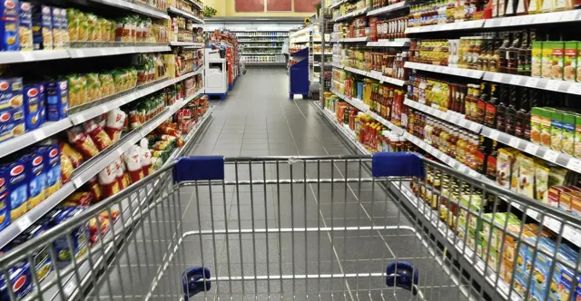 A cart is being pushed down an aisle in a grocery store.